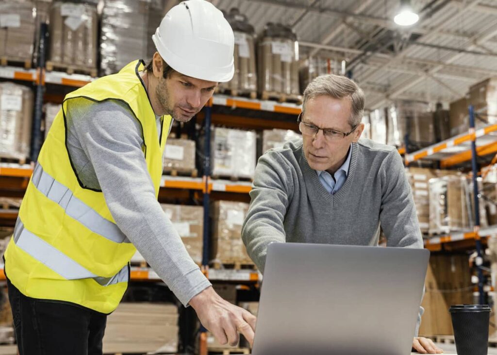 Men in Warehouse Working on a Laptop